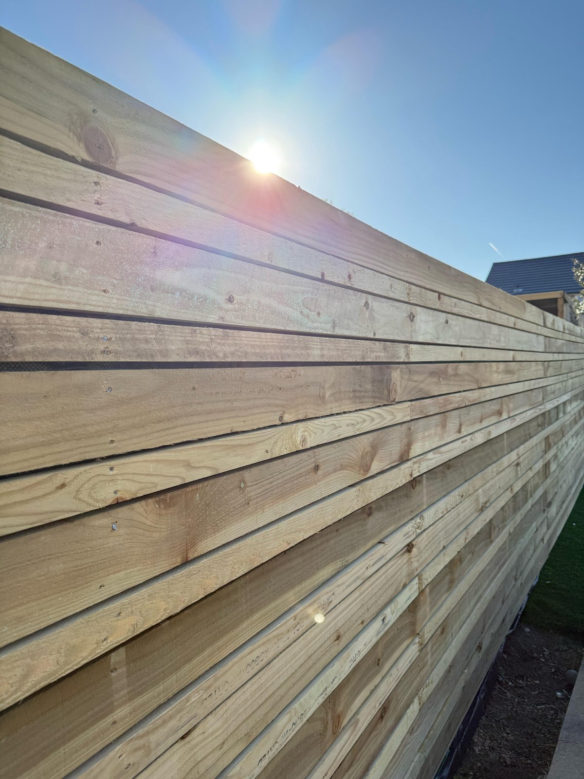 Close-board timber fence with sun flare